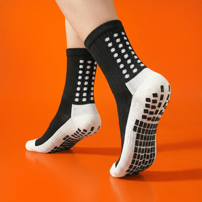 Black grip socks worn on an orange background, showing non-slip sole pads.