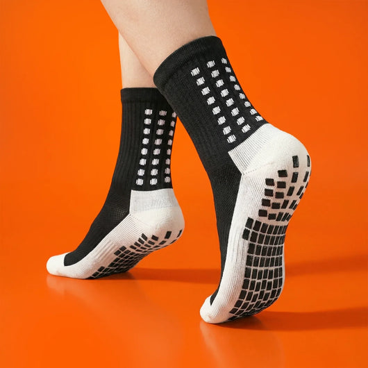 Black grip socks worn on an orange background, showing non-slip sole pads.