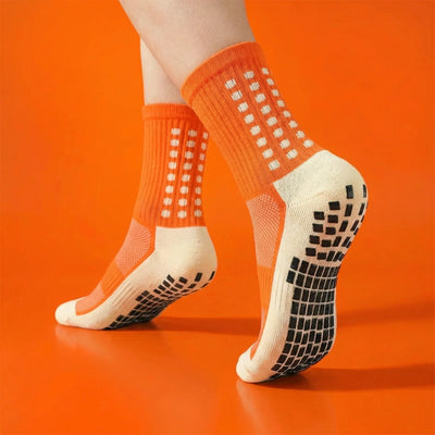 Orange grip socks worn on an orange background, showing non-slip sole pads.