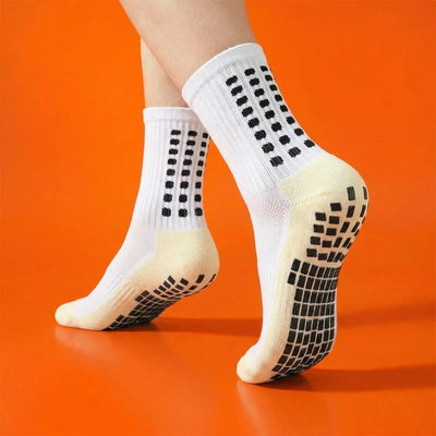 White grip socks worn on an orange background, showing non-slip sole pads.