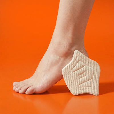 Beige heel cushion pad positioned under a foot on an orange background, designed for comfort and support.