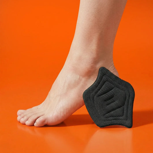 Black heel cushion pad positioned under the heel of a bare foot on an orange background.